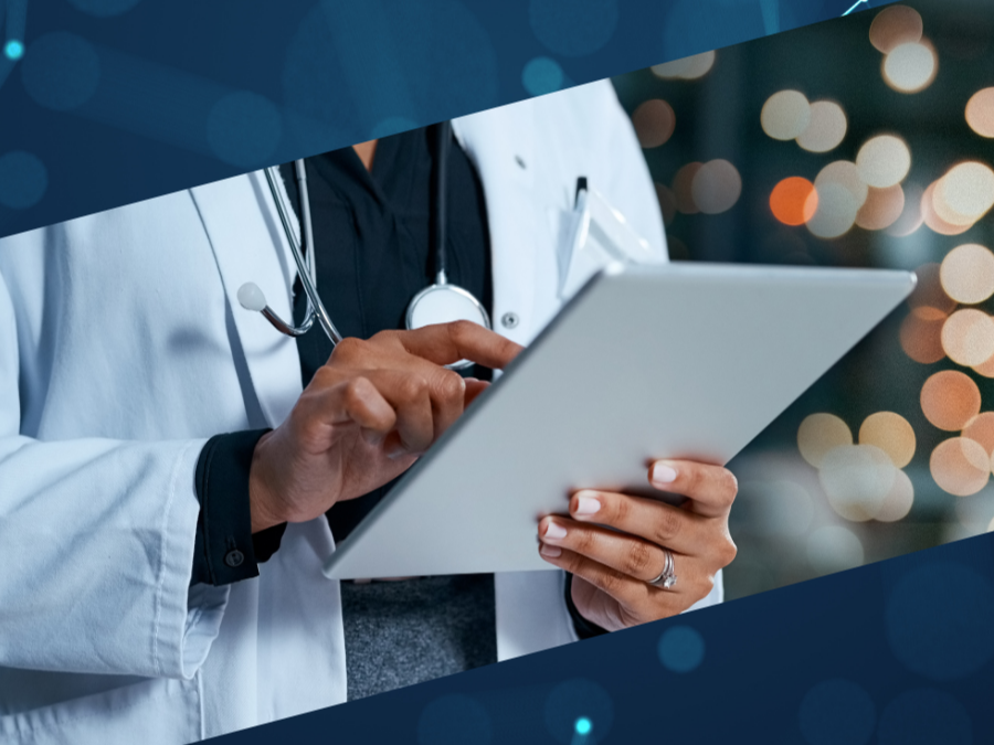 A doctor in a white coat with a stethoscope around their neck holding and using a tablet device.