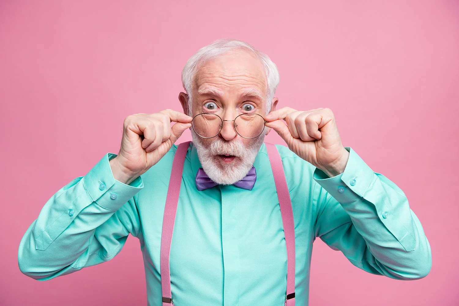 Senior gentlemen with teal shirt and pink suspenders tipping his glasses down