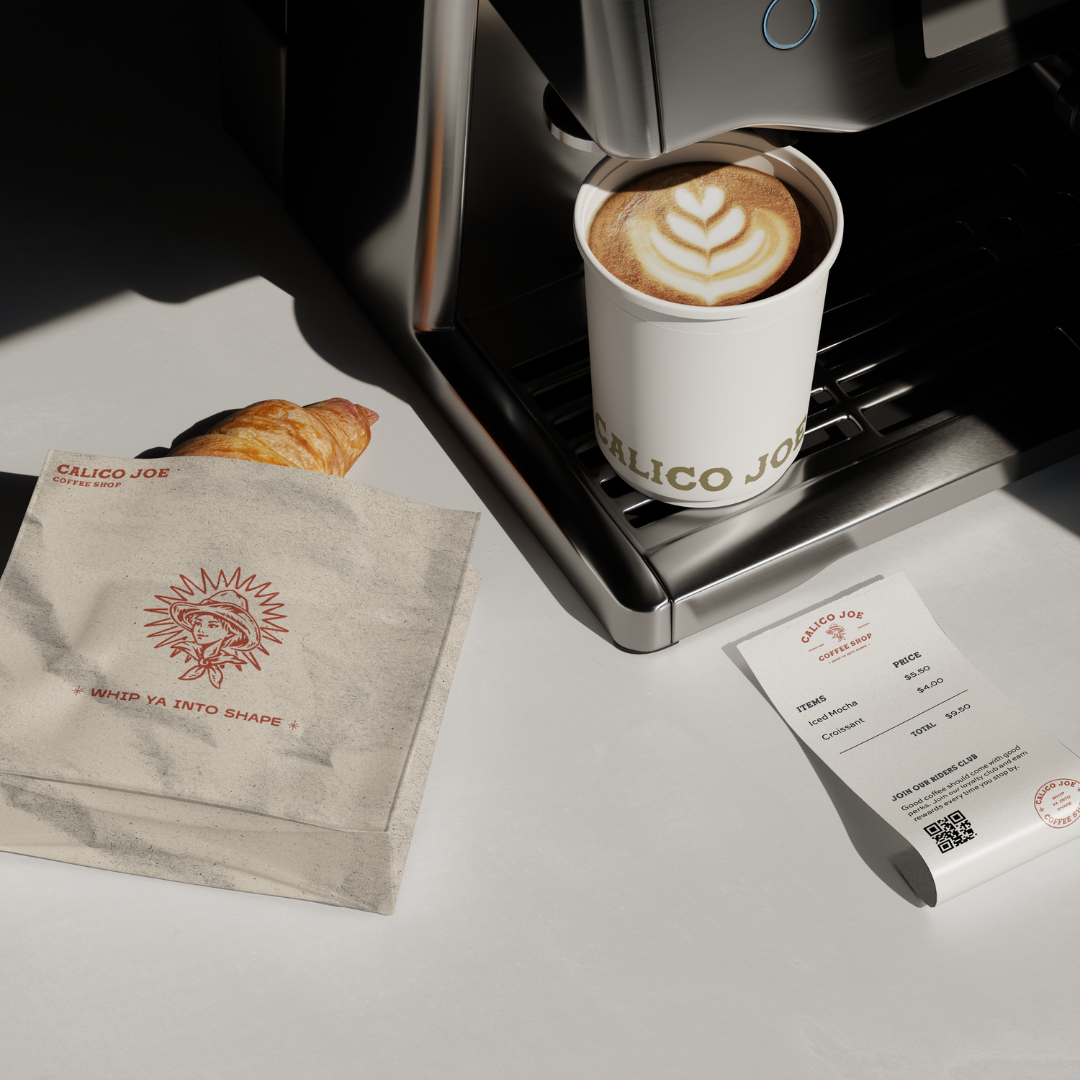 A cup of latte with latte art next to a croissant and a receipt on a white surface, with a coffee machine in the background.