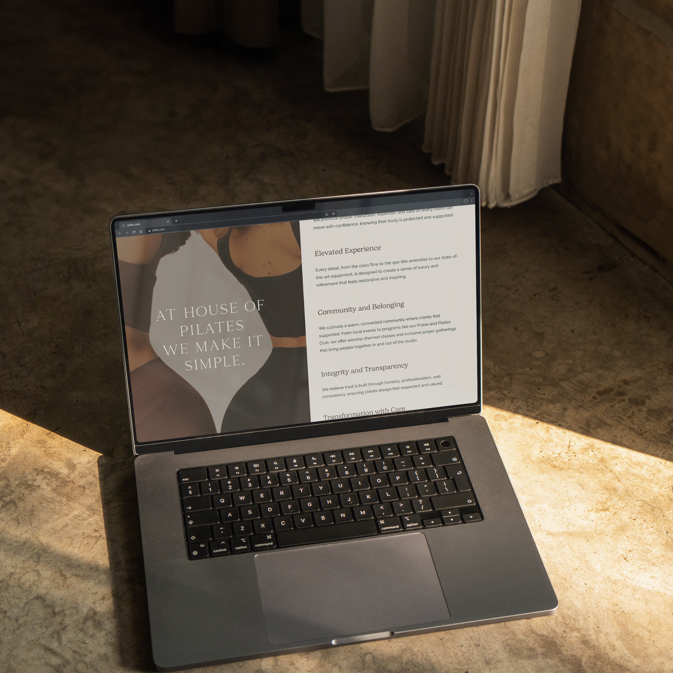Open laptop on a stone floor with sunlight shining on it. The screen displays a website for a Pilates studio with the text "At House of Pilates We Make It Simple."