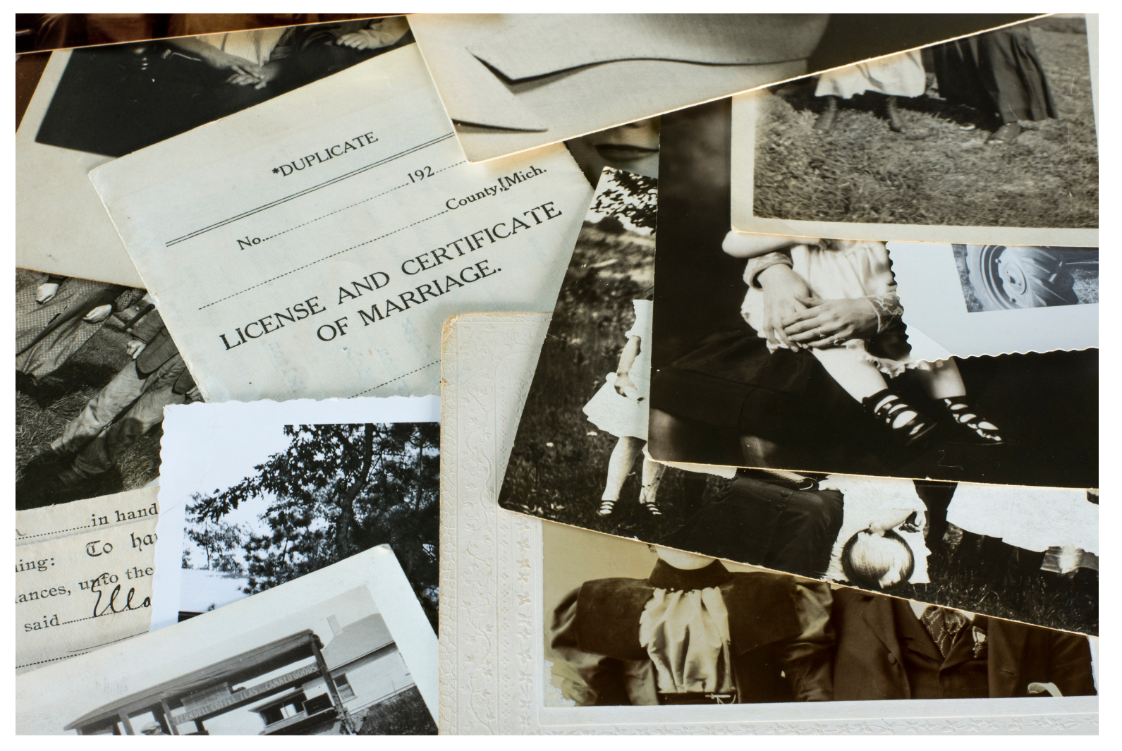 A collection of vintage black-and-white photographs, a marriage license, and various personal memorabilia arranged in a disorganized manner.