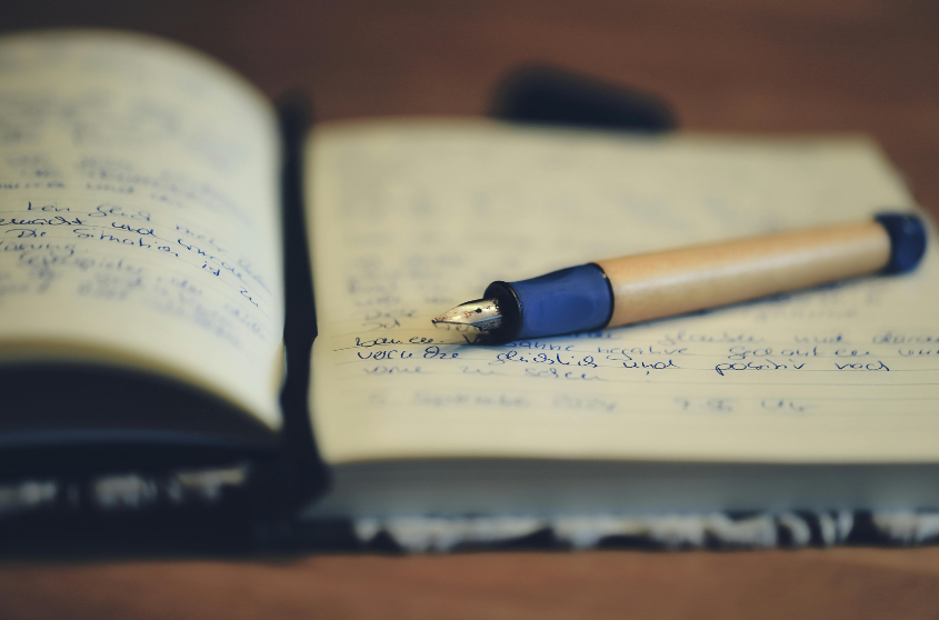 Open notebook with handwritten notes and a pen resting on it.