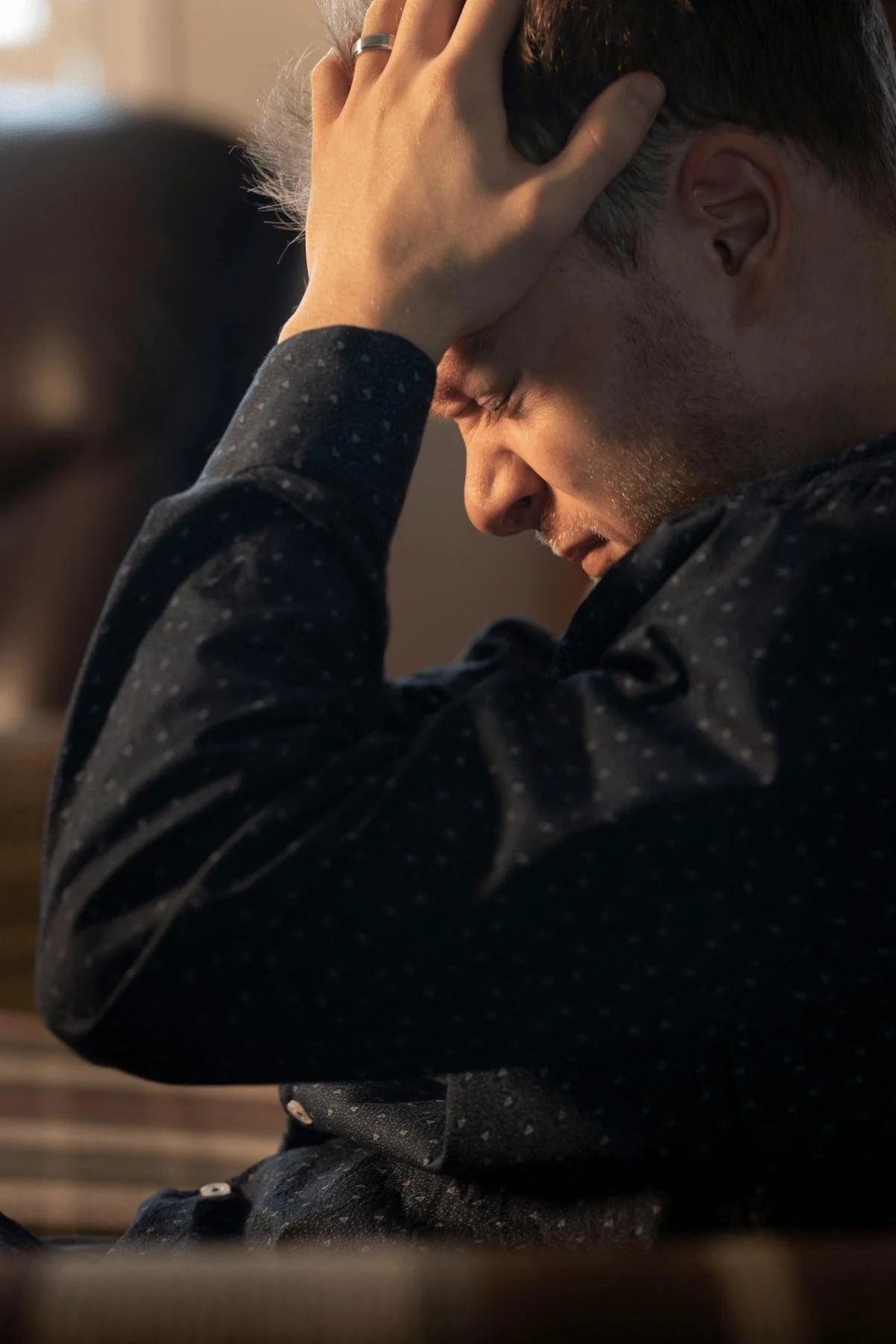 man looking stressed with hand on head black shirt