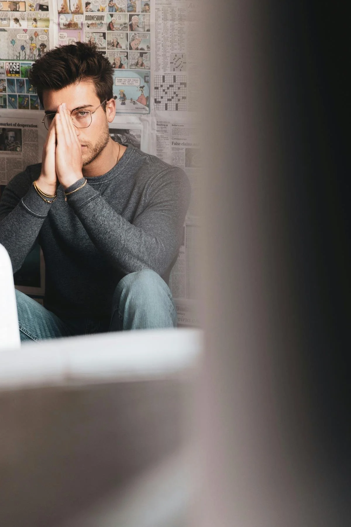 man sitting in corner of room with hands on nose looking dejected
