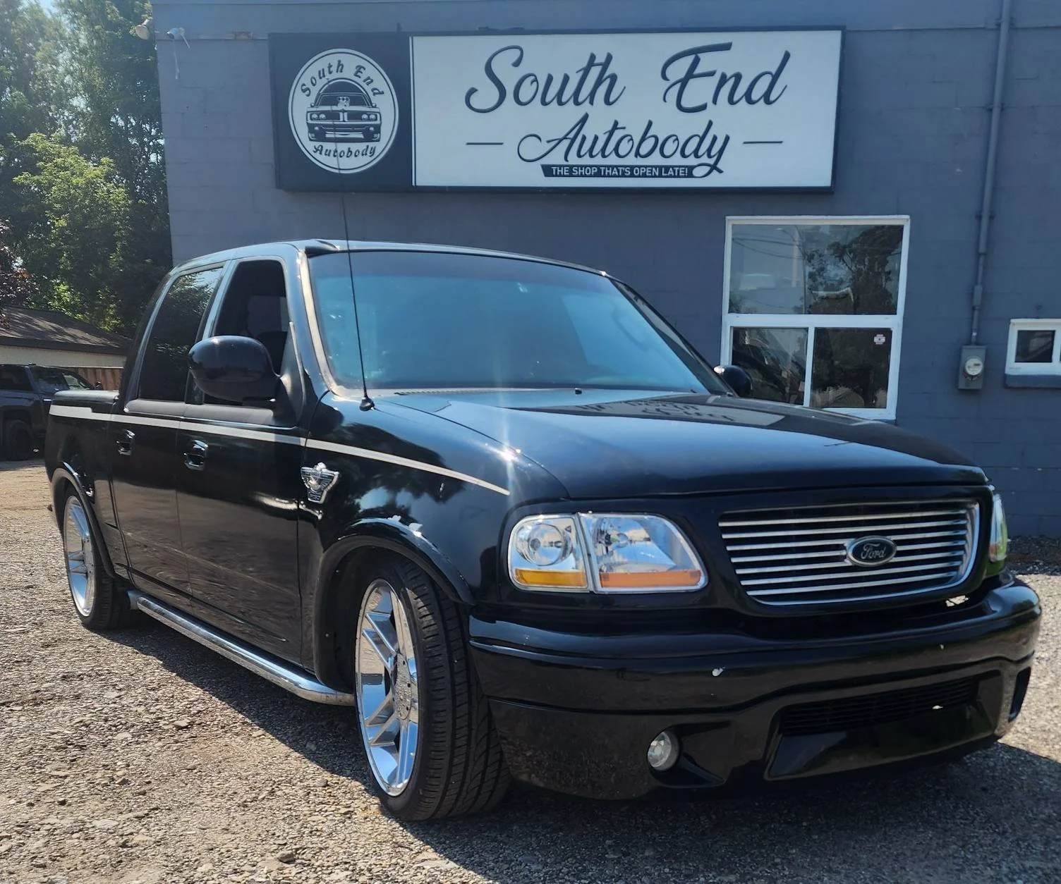Black Ford pickup truck parked outside South End Autobody shop