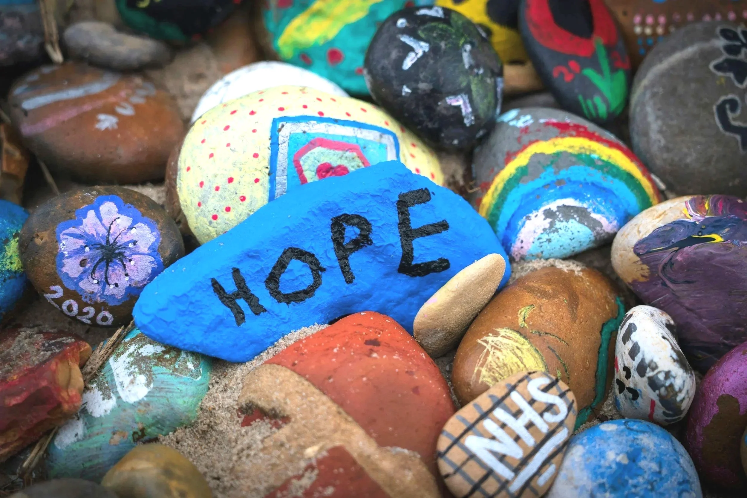 Colorful painted rocks, one with the word 'HOPE' written on it.