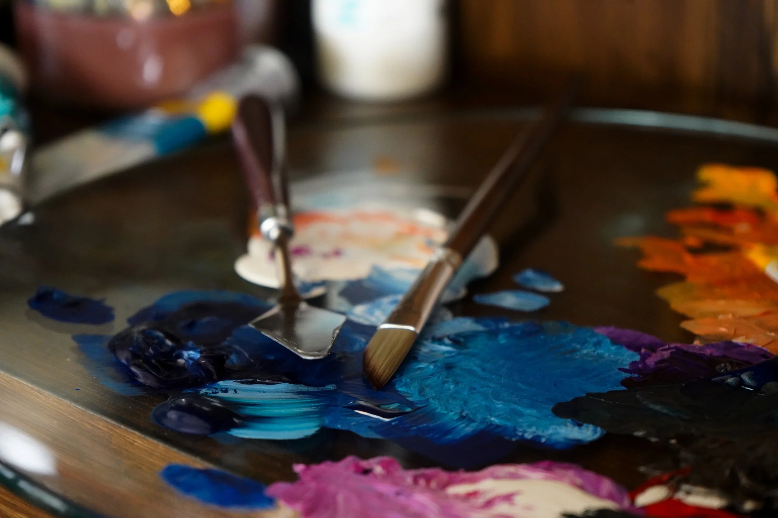 Close-up photograph of acrylic paint and palette knives on an artist's paint palette.