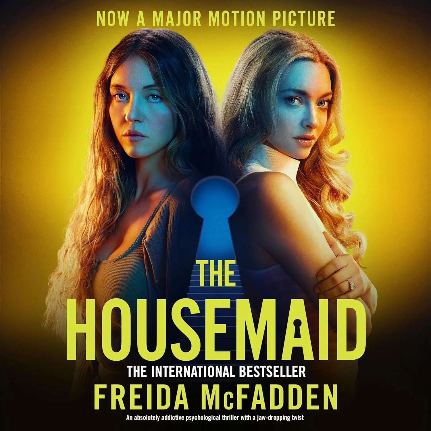 Book cover for 'The Housemaid' by Freida McFadden featuring two women with long hair, one with dark and the other with blonde hair, standing back-to-back against a yellow background with a keyhole image in the center.