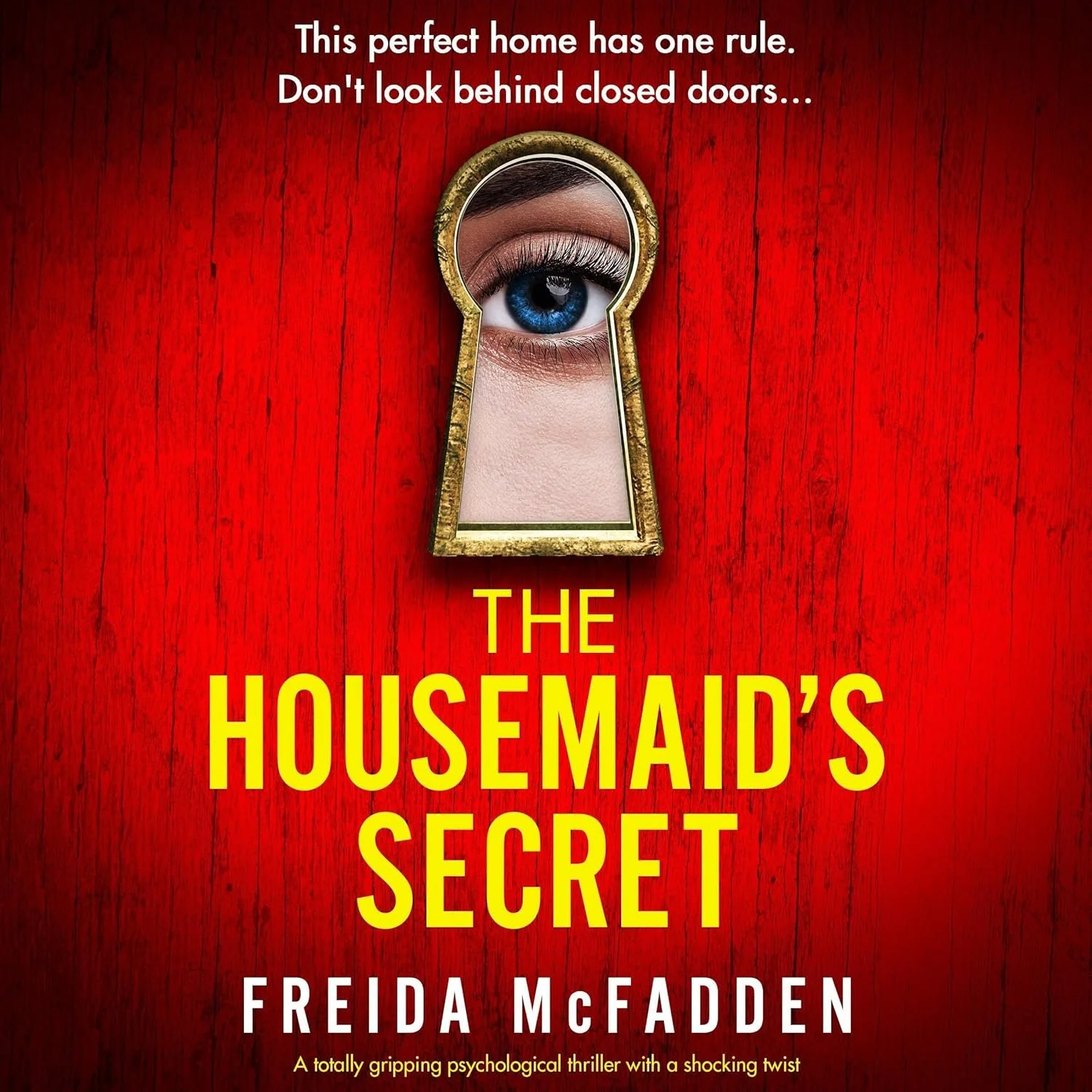 A book cover with a red wooden background, featuring a keyhole with a woman's eye visible through it, and the title 'The Housemaid's Secret' by Freida McFadden.