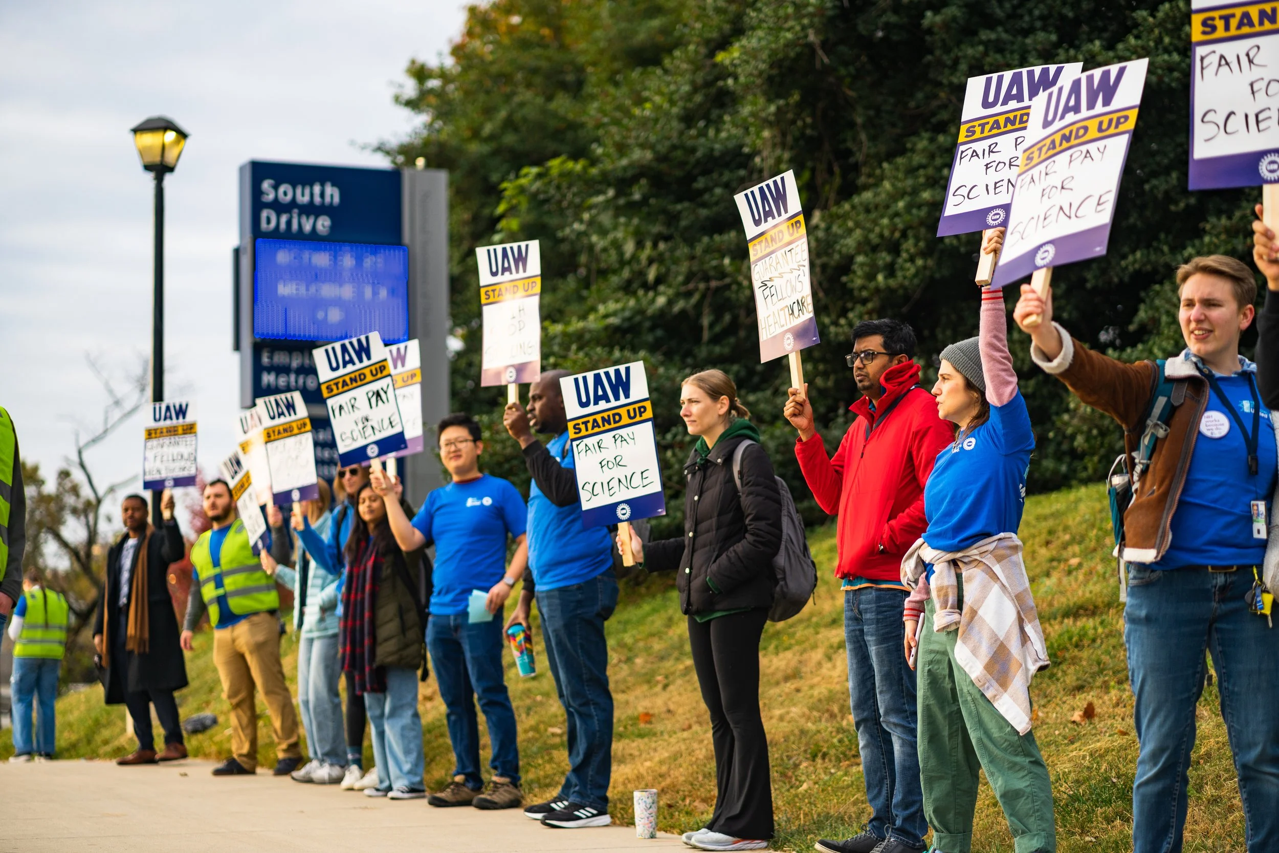 NIH Fellows holding UAW Stand Up signs calling for fair pay for science and guaranteed Fellows healthcare.