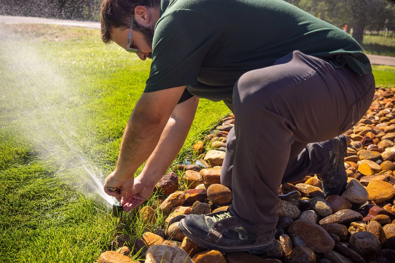 Man adjusting sprinkler spray pattern