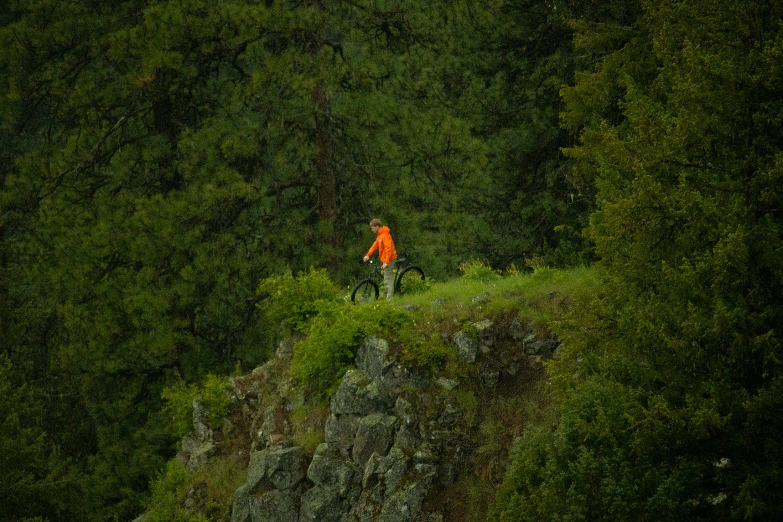 Modern house with wooden exterior and stone steps leading up to a patio, nestled in a mountainous landscape with snow-capped peaks in the distance.
