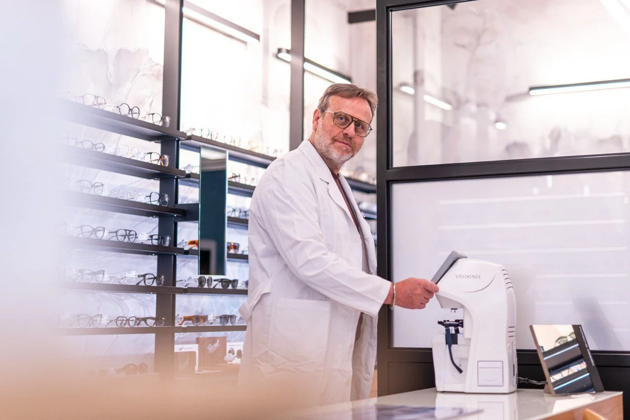 Uomo con occhiali in un negozio di ottica, che utilizza una macchina per misurare la lenti.
