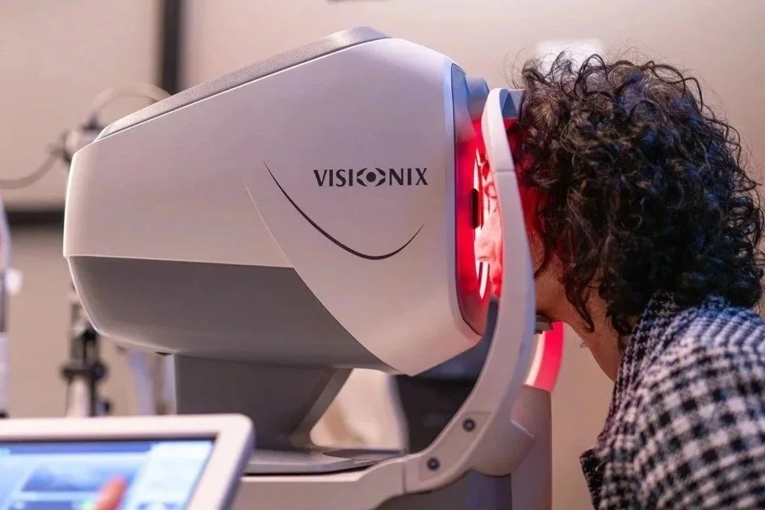 Persona che fa un esame oculistico con una macchina di tecnologia avanzata branded VISIONIX.
