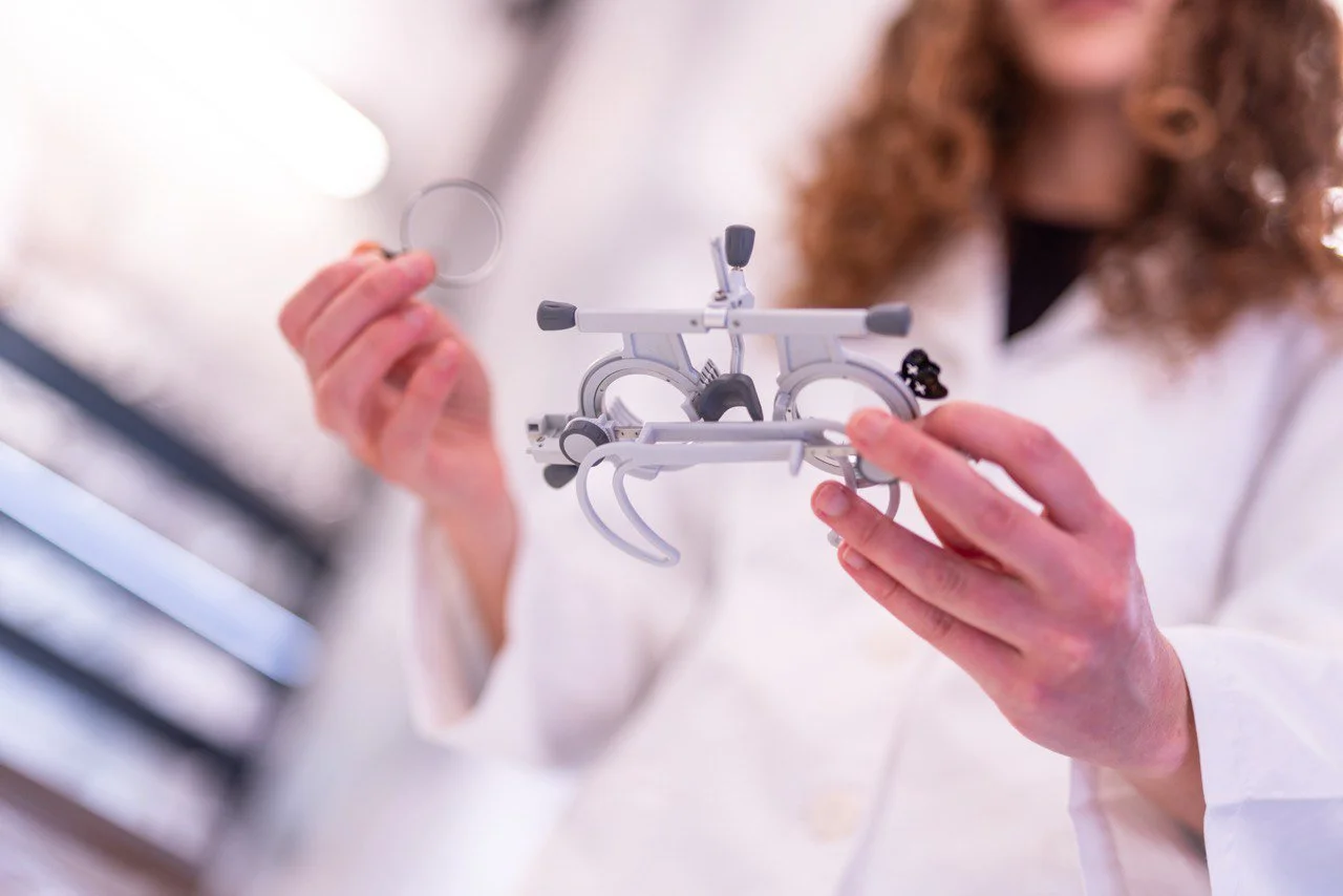 Una persona con camice bianco tiene in mano un modello didattico di un'apparecchiatura o dispositivo medico, utilizzato probabilmente per una visita ottica.