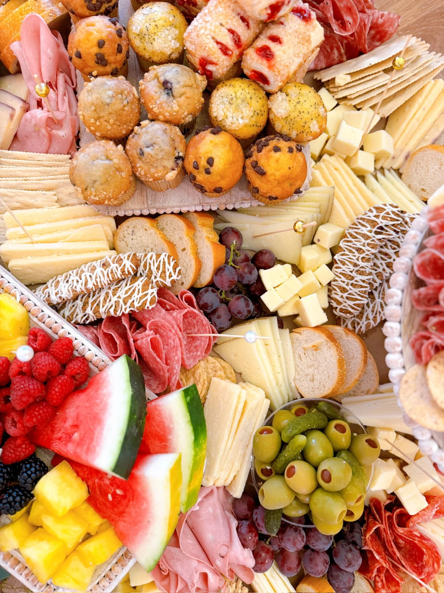 Assorted cheese, fruits, crackers, and meats platter with grapes, watermelon, pineapple, raspberries, blackberries, and various cheeses and charcuterie.