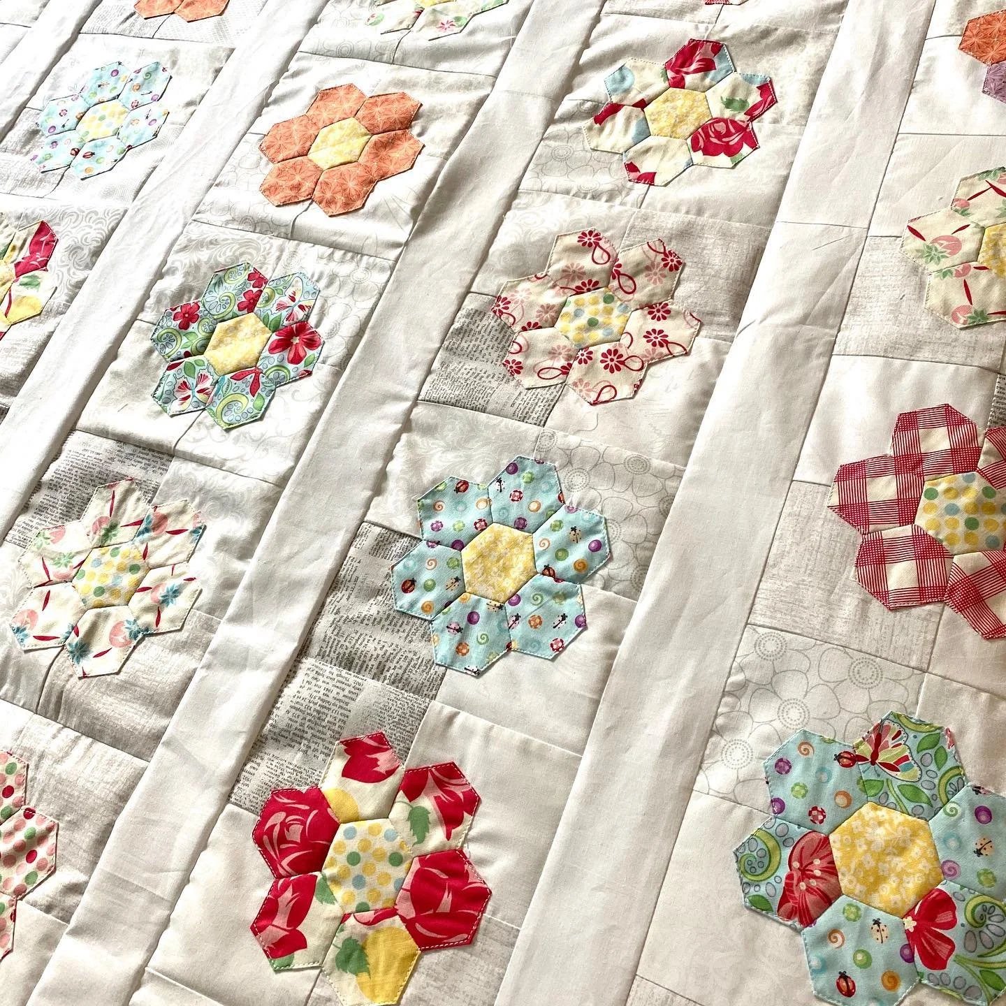 A quilt with colorful hexagon flower patterns on a white fabric background.