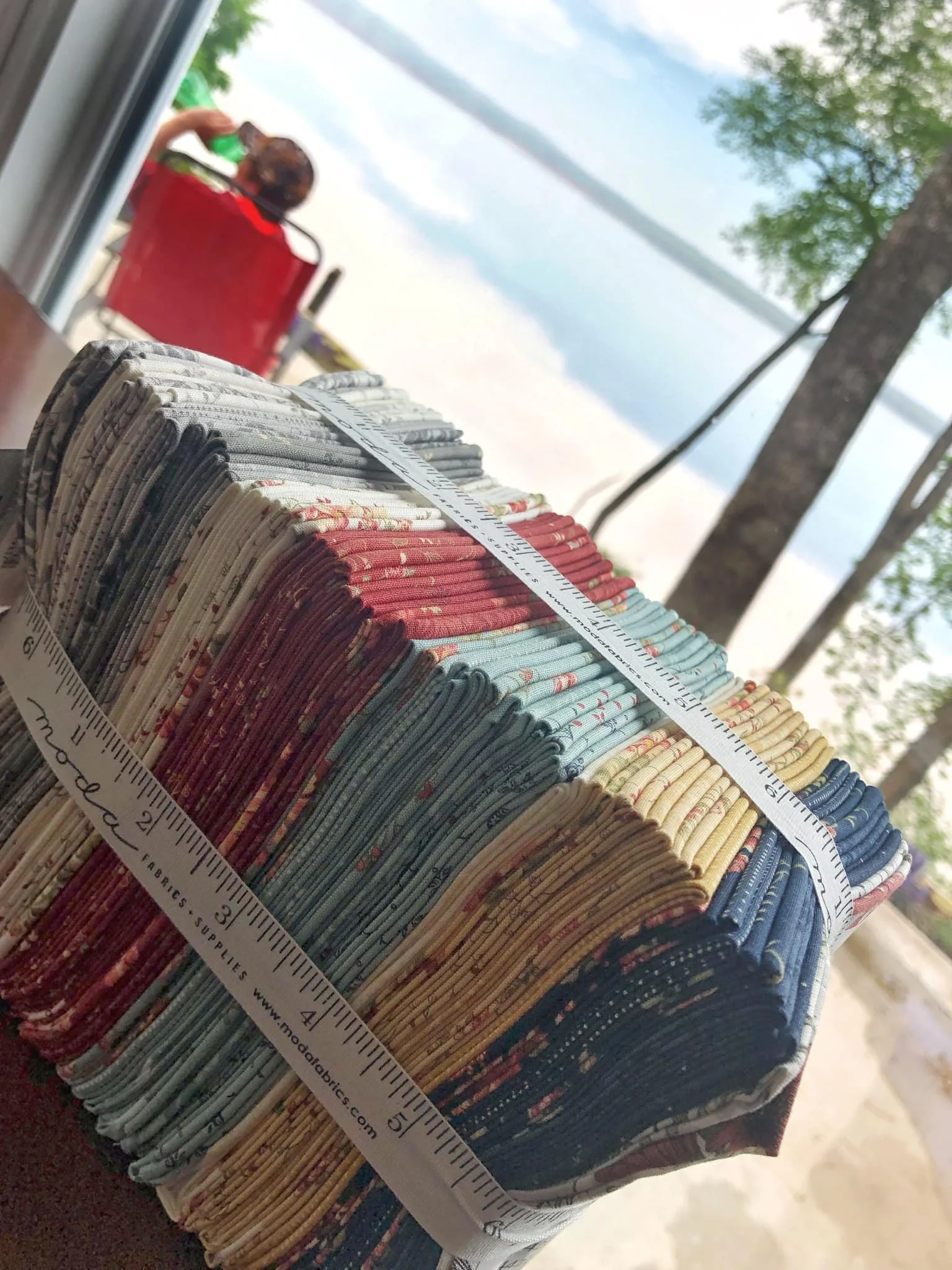 Assorted fabric pieces with floral and geometric patterns arranged on a cutting mat with rulers. 