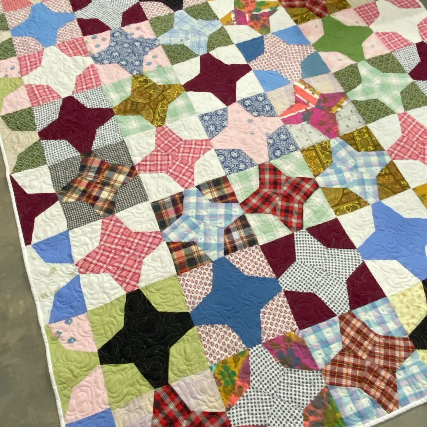 A colorful patchwork quilt with various patterned fabric blocks in different shapes and colors.