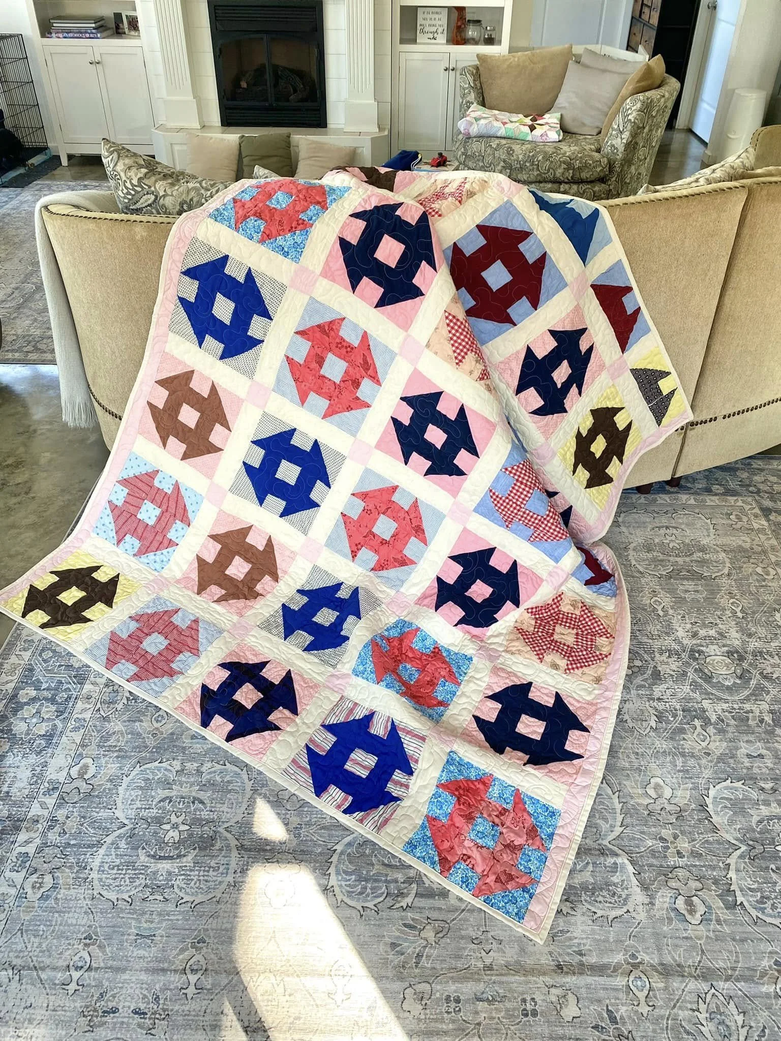 Colorful patchwork quilt with geometric patterns draped over a beige couch in a living room.