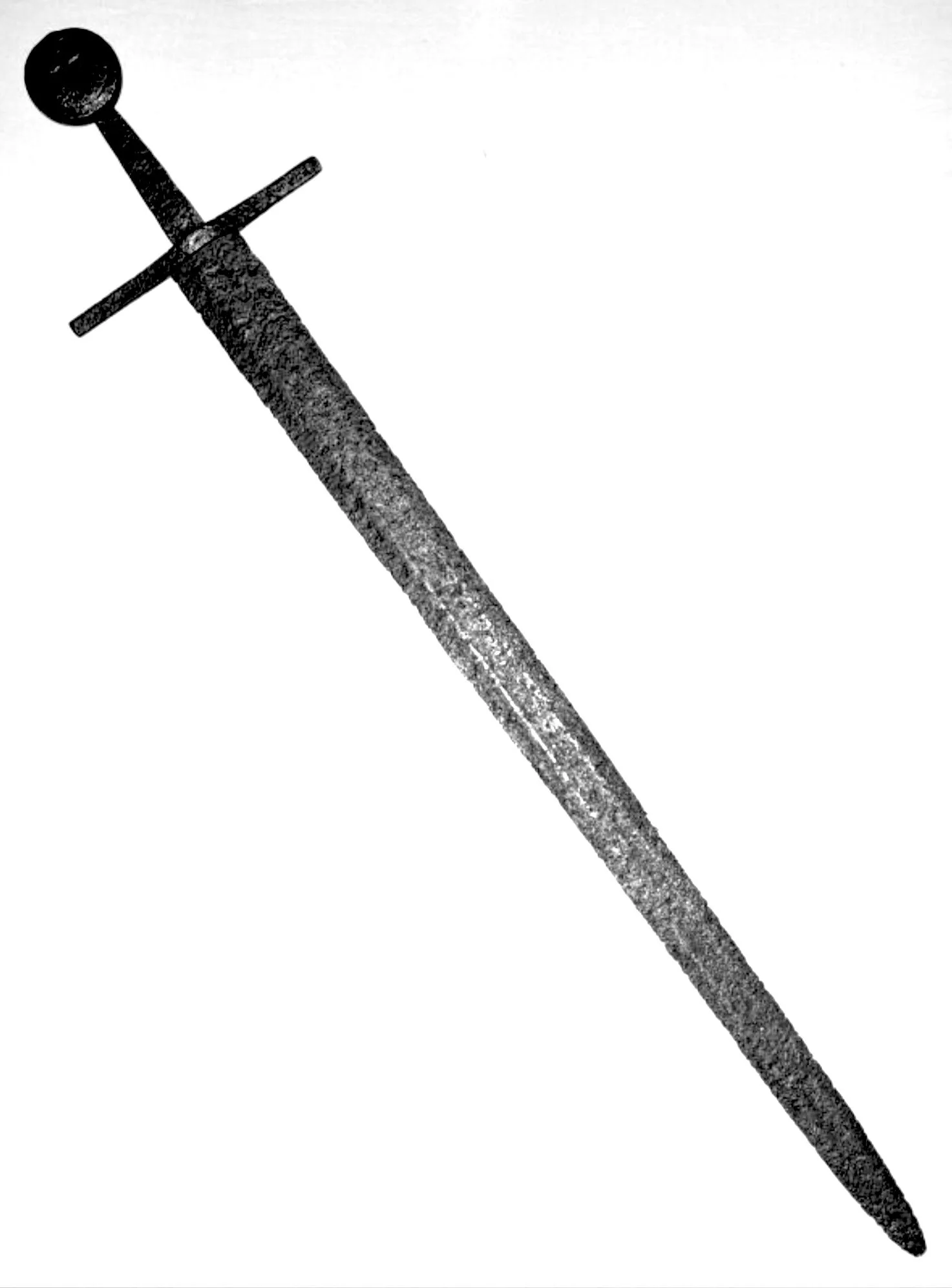 Black and white image of an old, rusty sword with a round pommel and a crossguard, positioned at an angle against a plain white background.