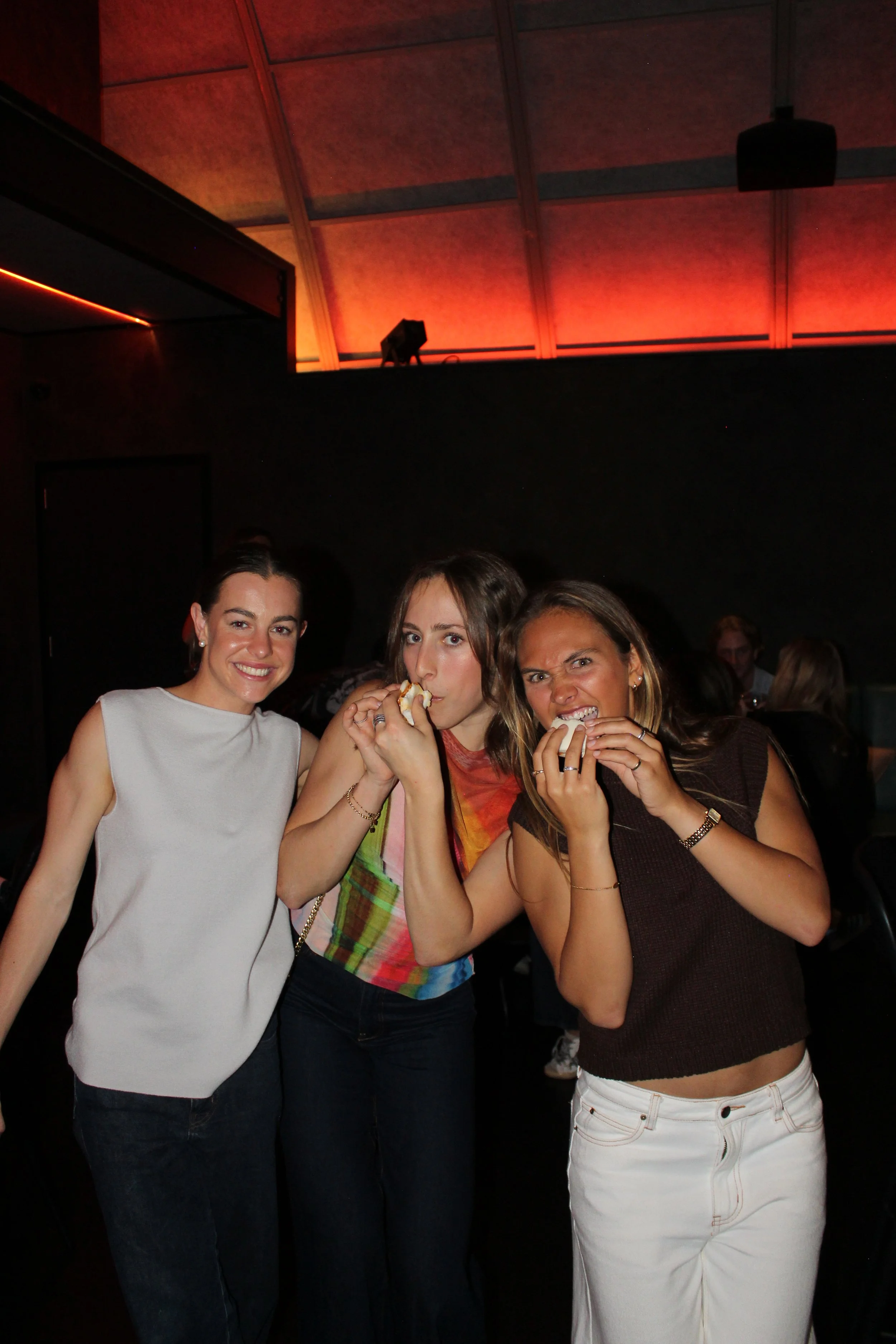 Three women enjoying snacks at a social gathering or party.