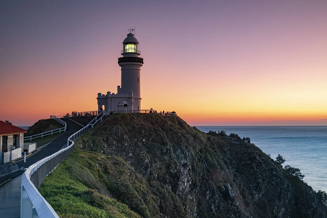 Lighthouse on a cliff at sunset, overlooking the ocean.