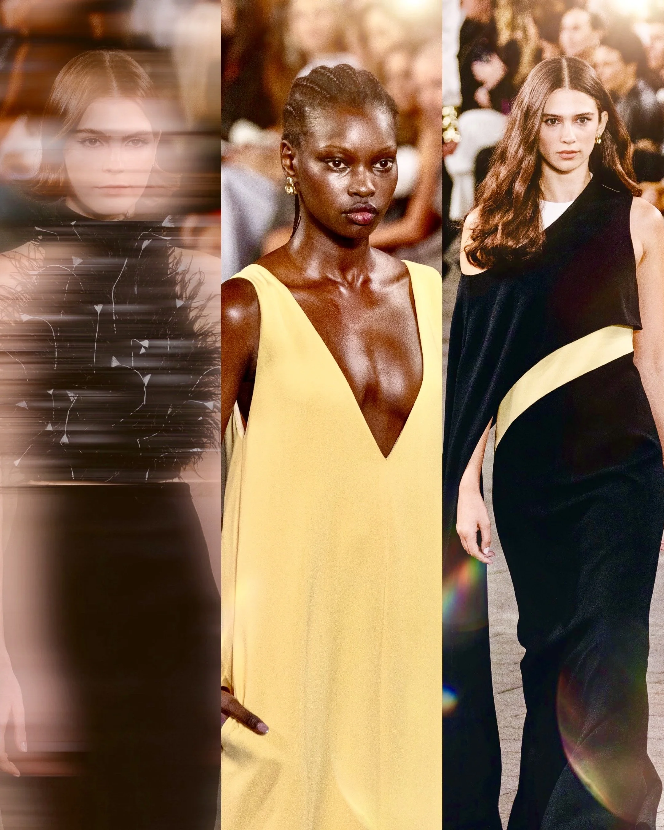 Three women walking on a runway wearing fashionable dresses, with an audience and bright lights in the background.