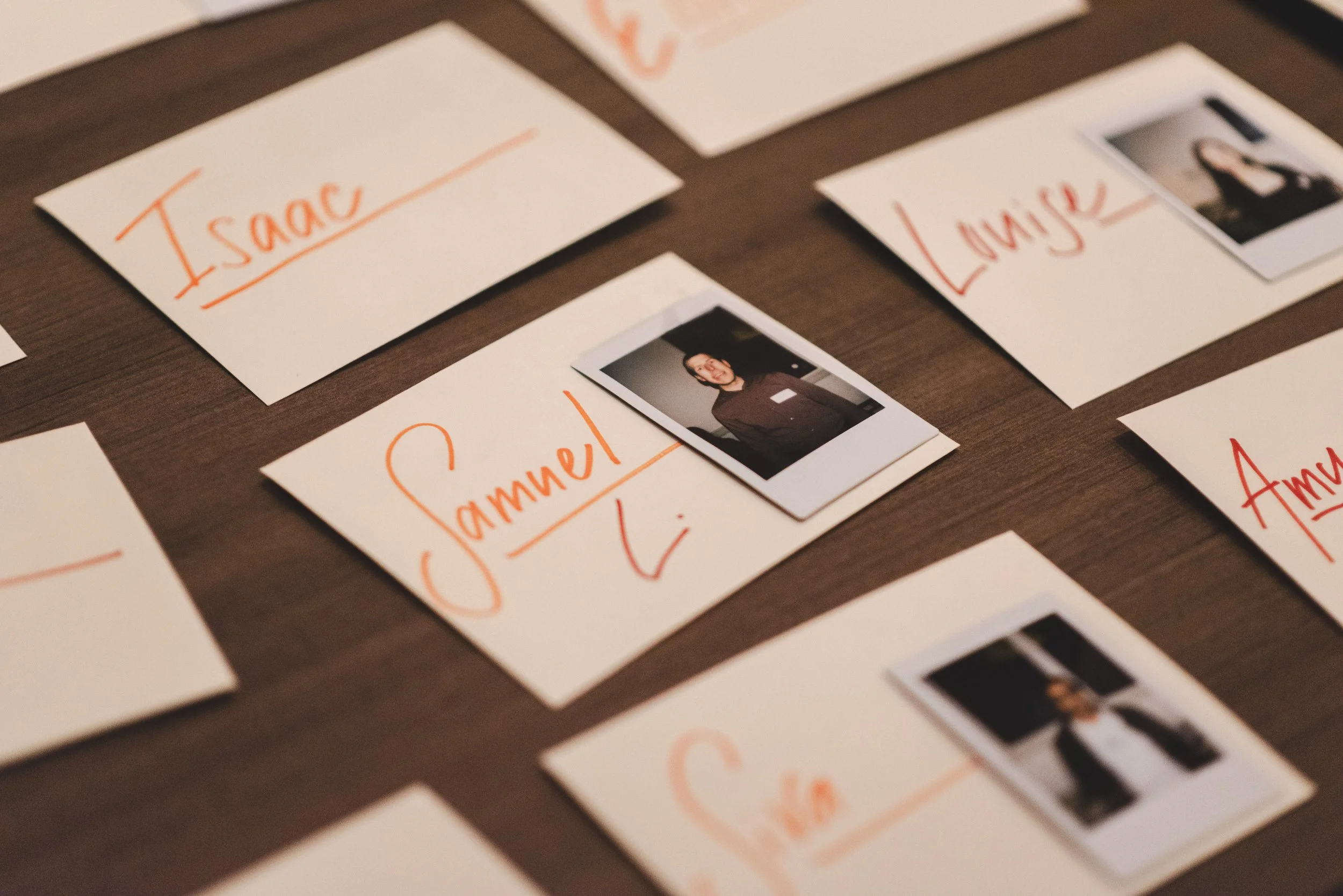 Several pieces of paper with names handwritten in orange ink, including "Isaac," "Samuel," "Lynne," and "Amy." A small photograph of a woman is attached to one of the papers.