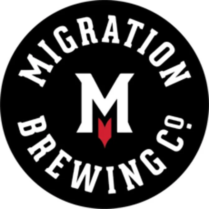 Black circular logo with white text reading 'Migration Brewing Co.' surrounding a central white letter 'M' with a red downward arrow shape.