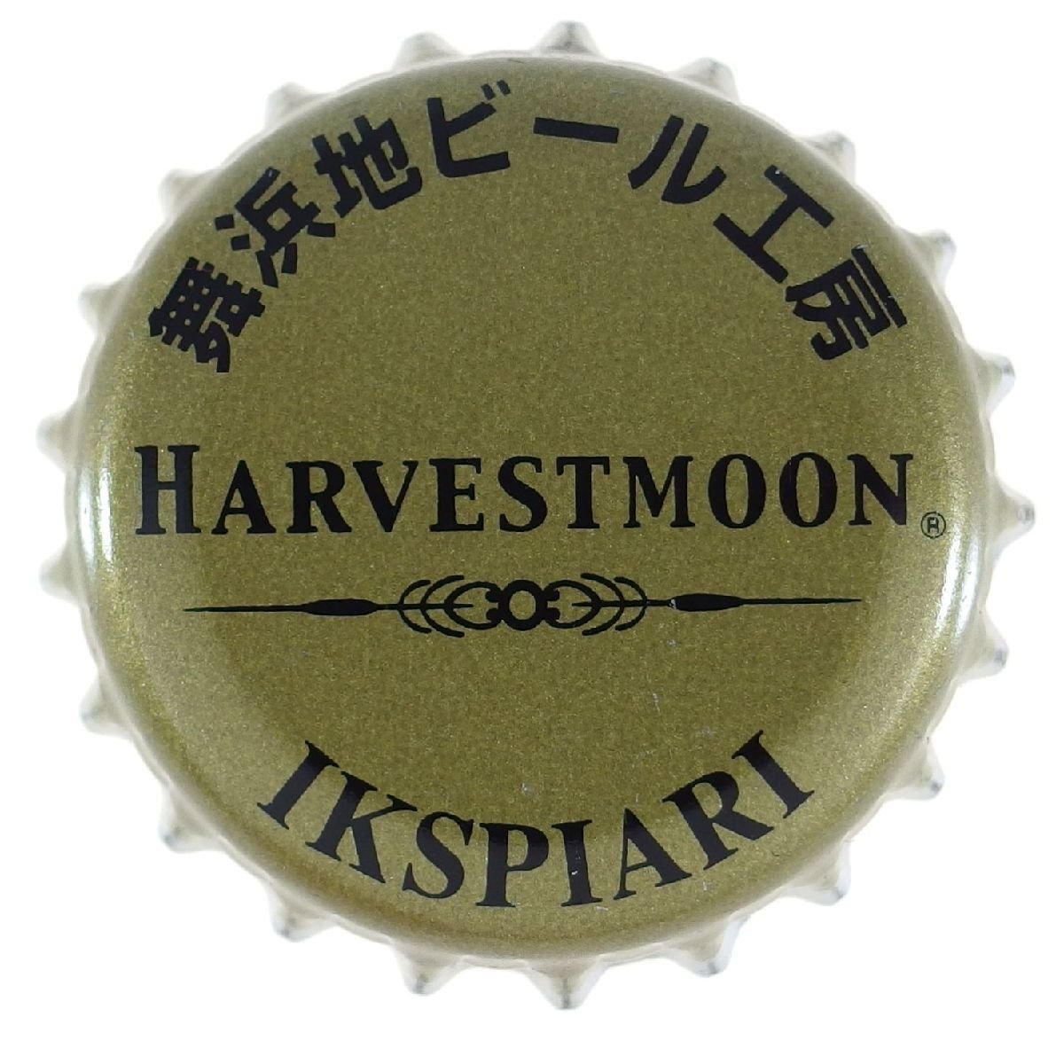 Metal bottle cap with black text in English and Japanese and decorative lines, featuring the words 'HARVESTMOON' and 'IKSPIARI.'