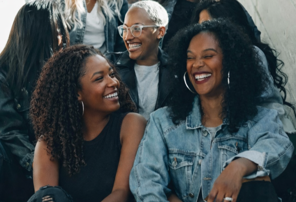 Group of diverse young adults smiling and laughing together outside.