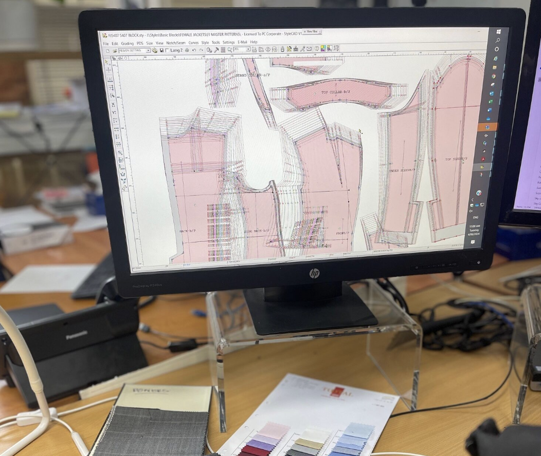 Computer monitor displaying technical fabric pattern design with pink shaded areas and detailed sewing lines.