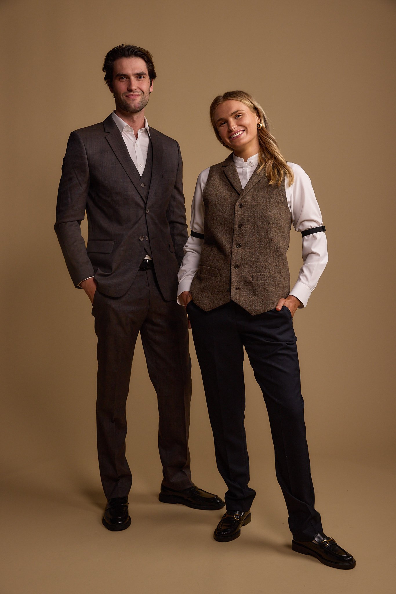 A man and woman standing side by side in professional attire against a plain background, smiling at the camera.