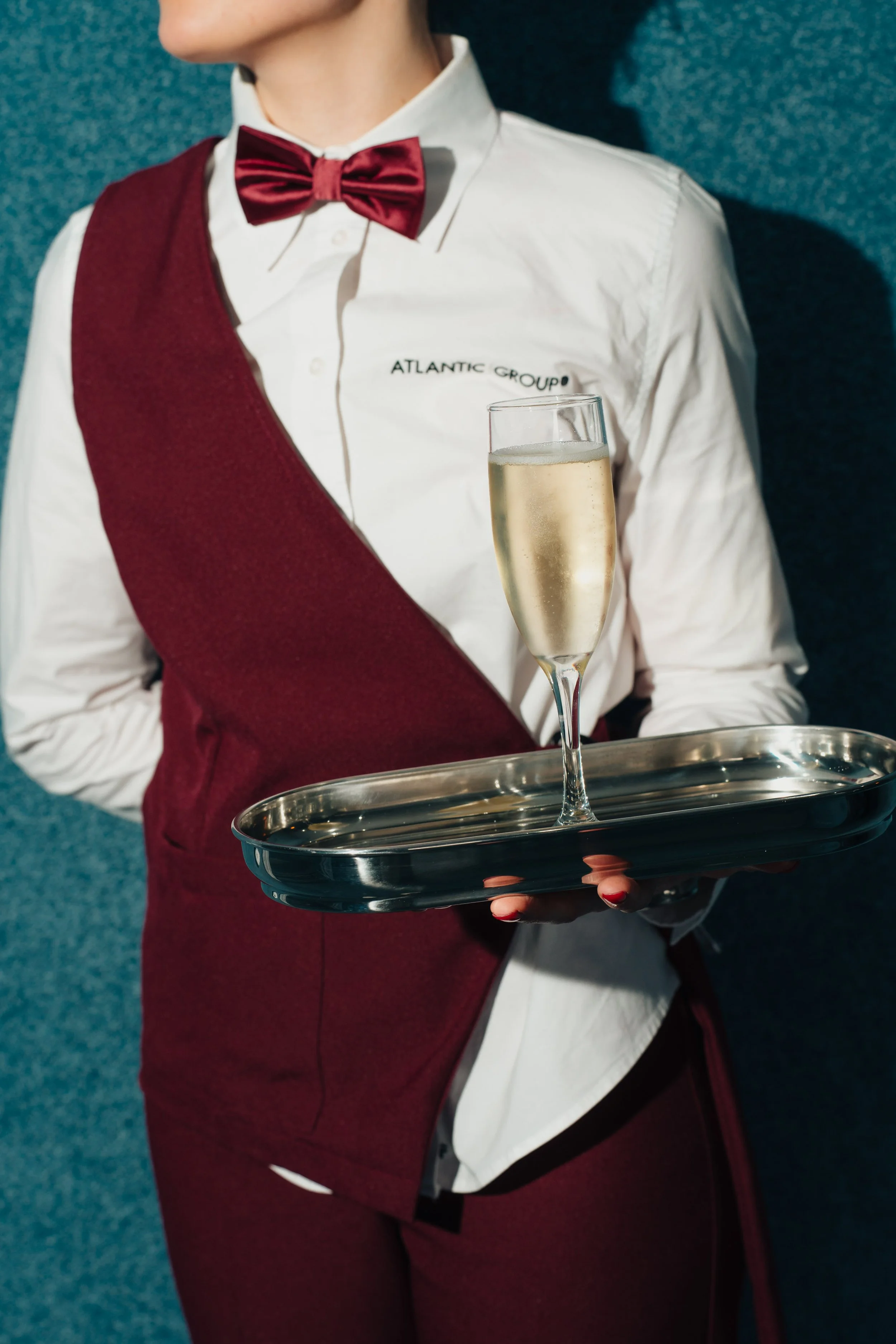 Waitress in uniform holding a tray with a glass of champagne.