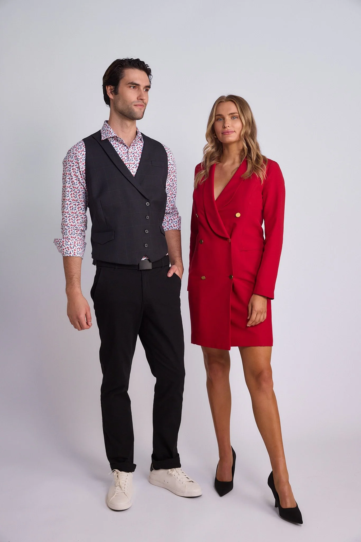 A man and woman dressed in business attire standing against a plain white background.