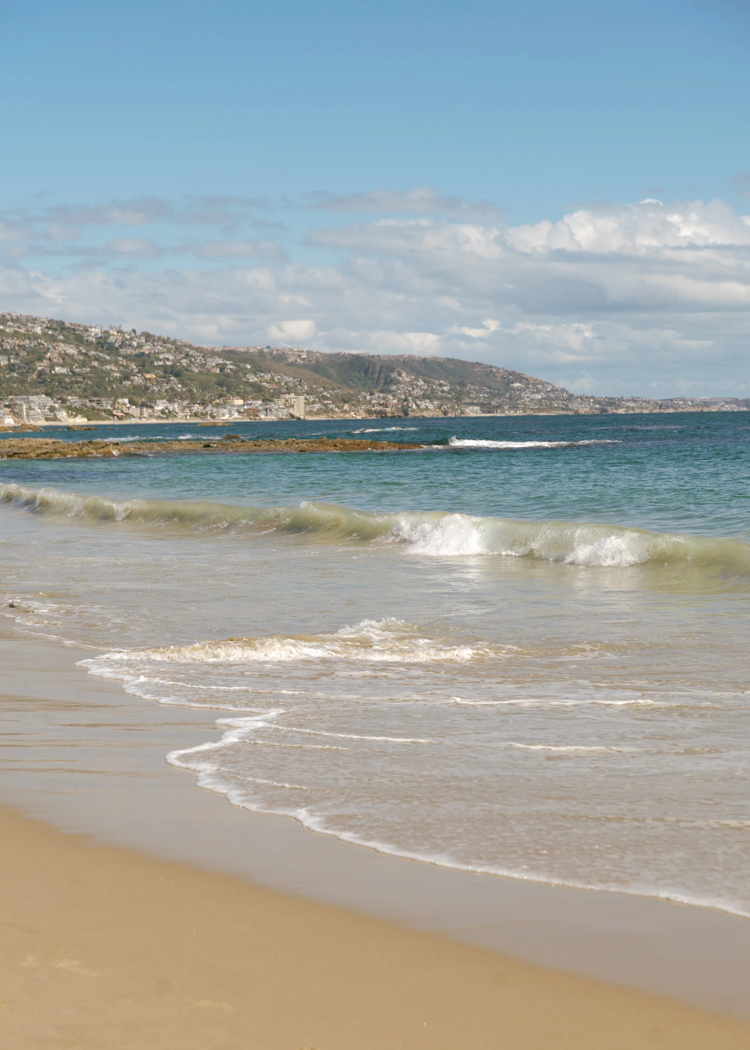 Picture of waves crashing into shore with a coastal skyline.