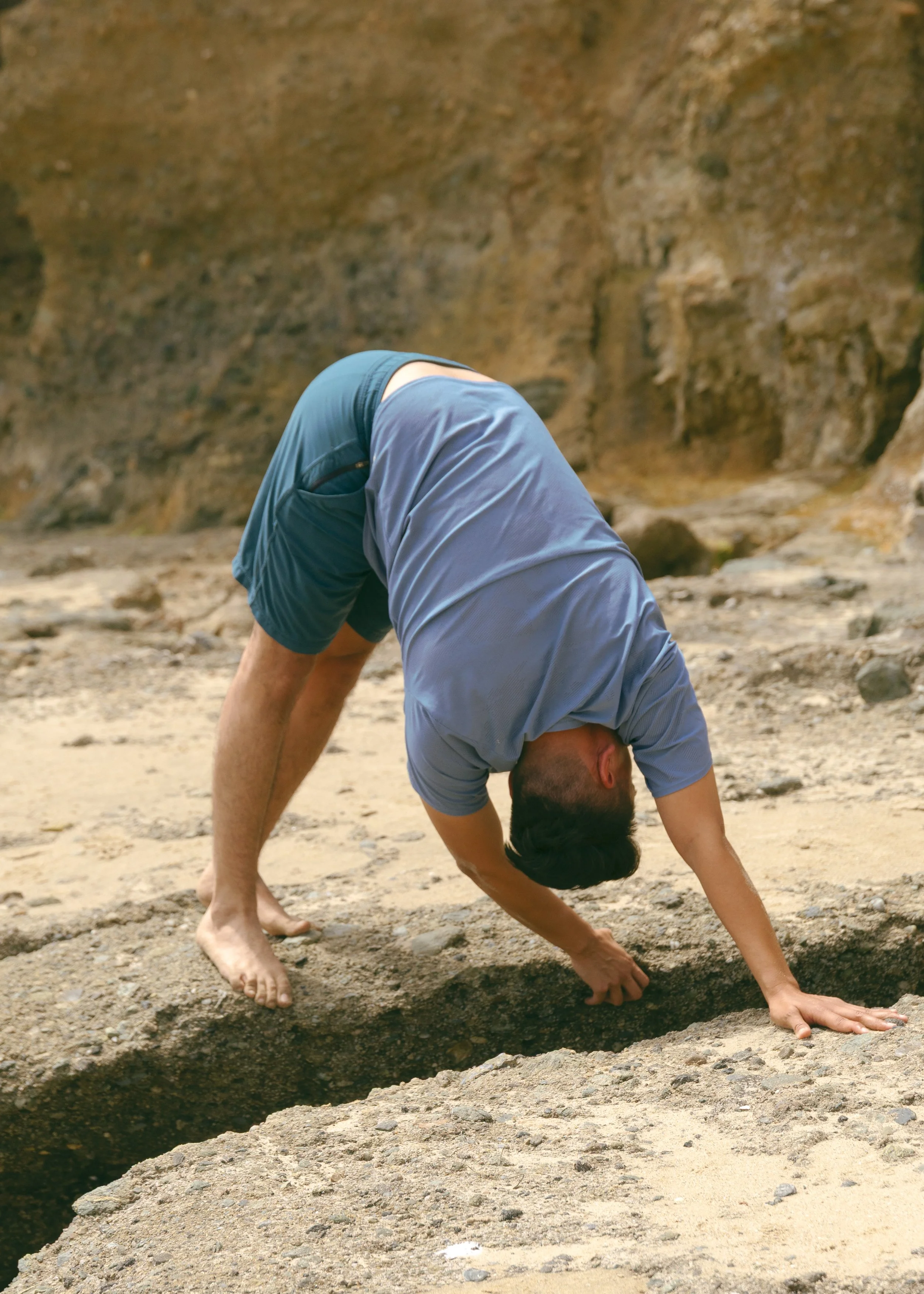 Photo of a man in an upside down stretch on the beach.