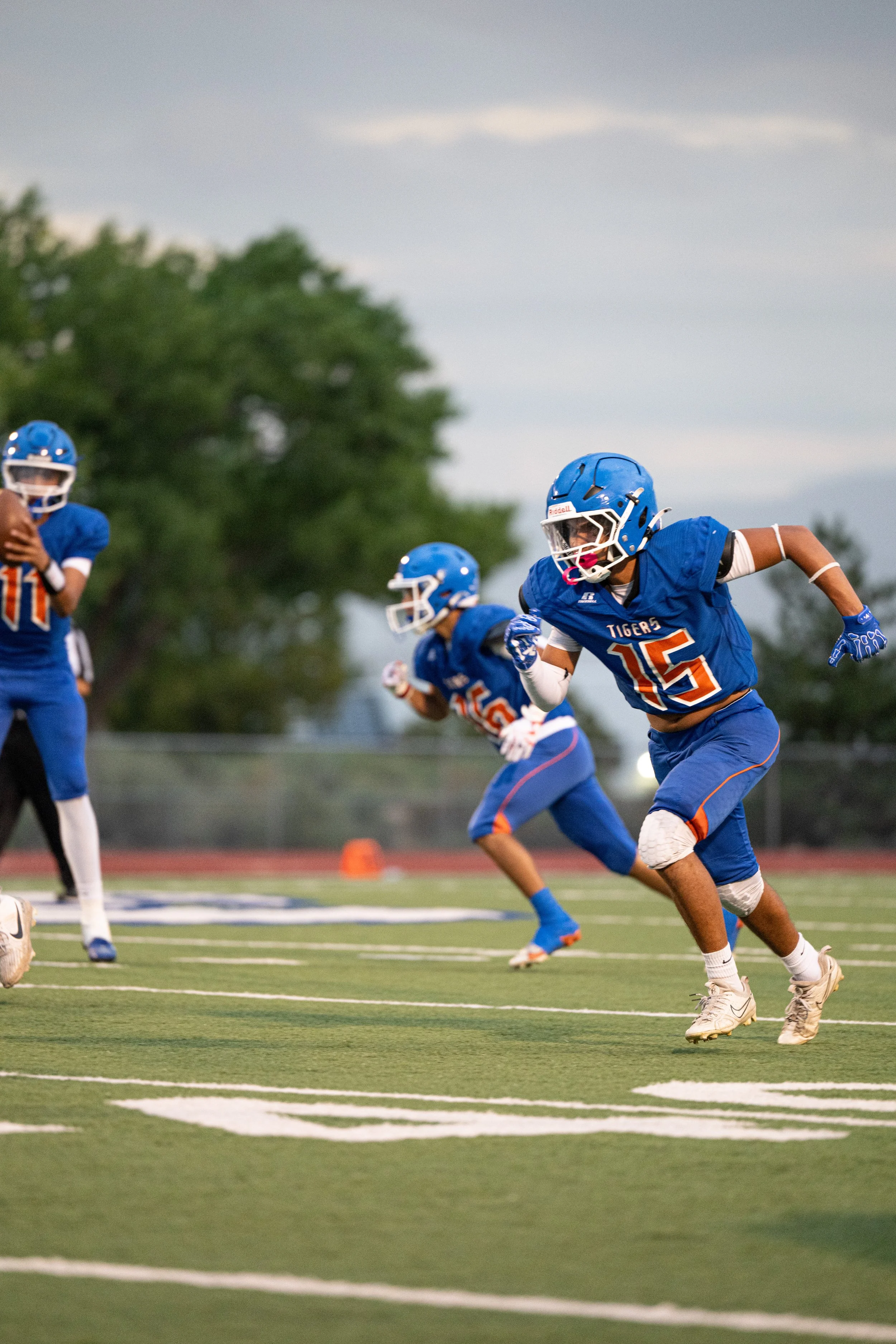 Football players in blue uniforms and protective gear running on the field during a game.