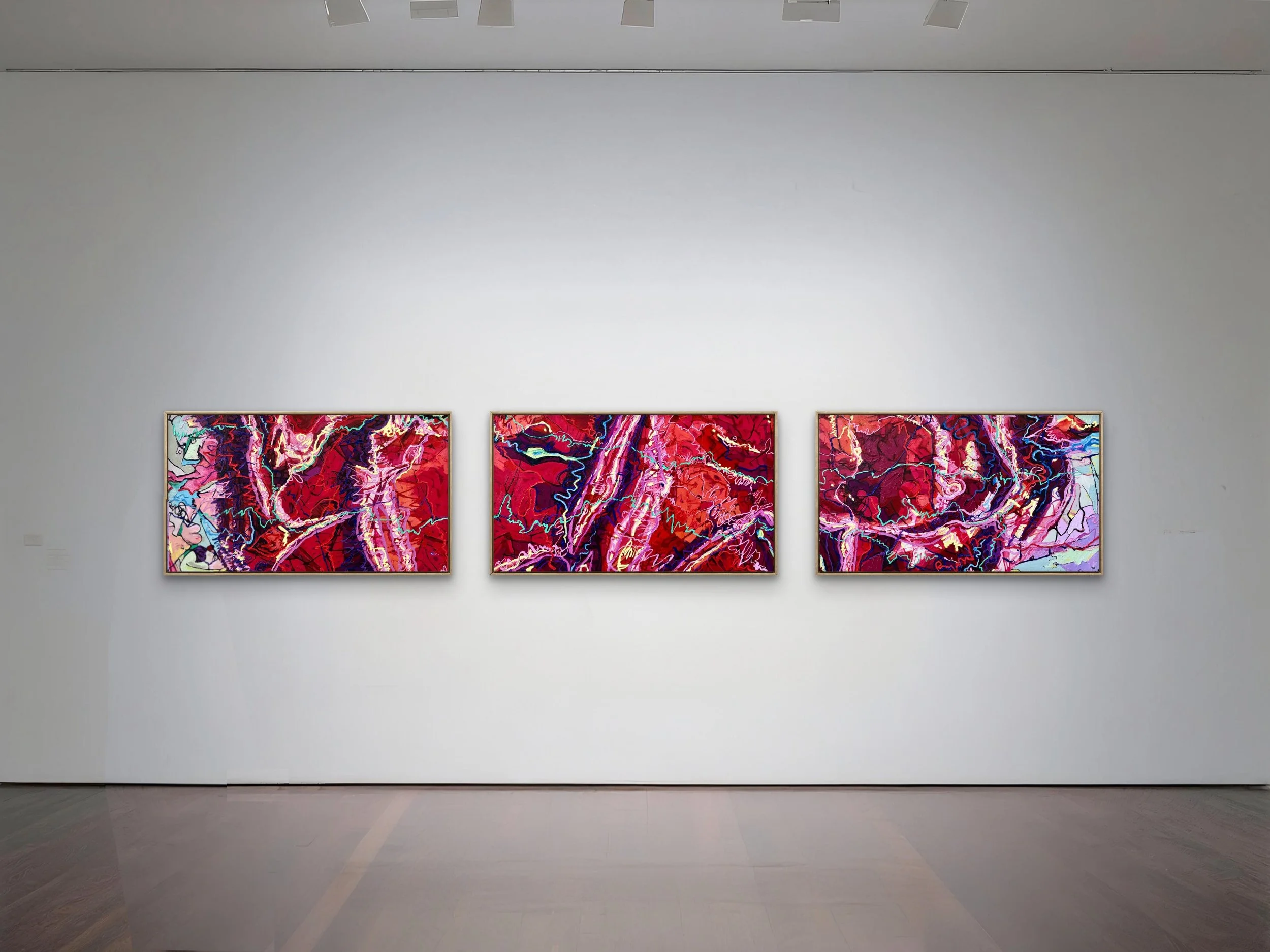 Three abstract paintings with vibrant reds, pinks, purples, and blues on display in a gallery with white walls.