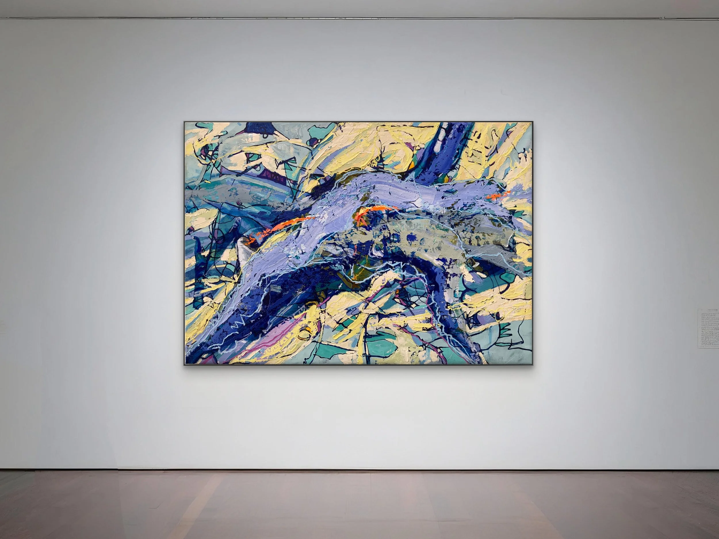 An abstract painting with vibrant blues, purple, yellow, and black strokes, displayed in a gallery with white walls.