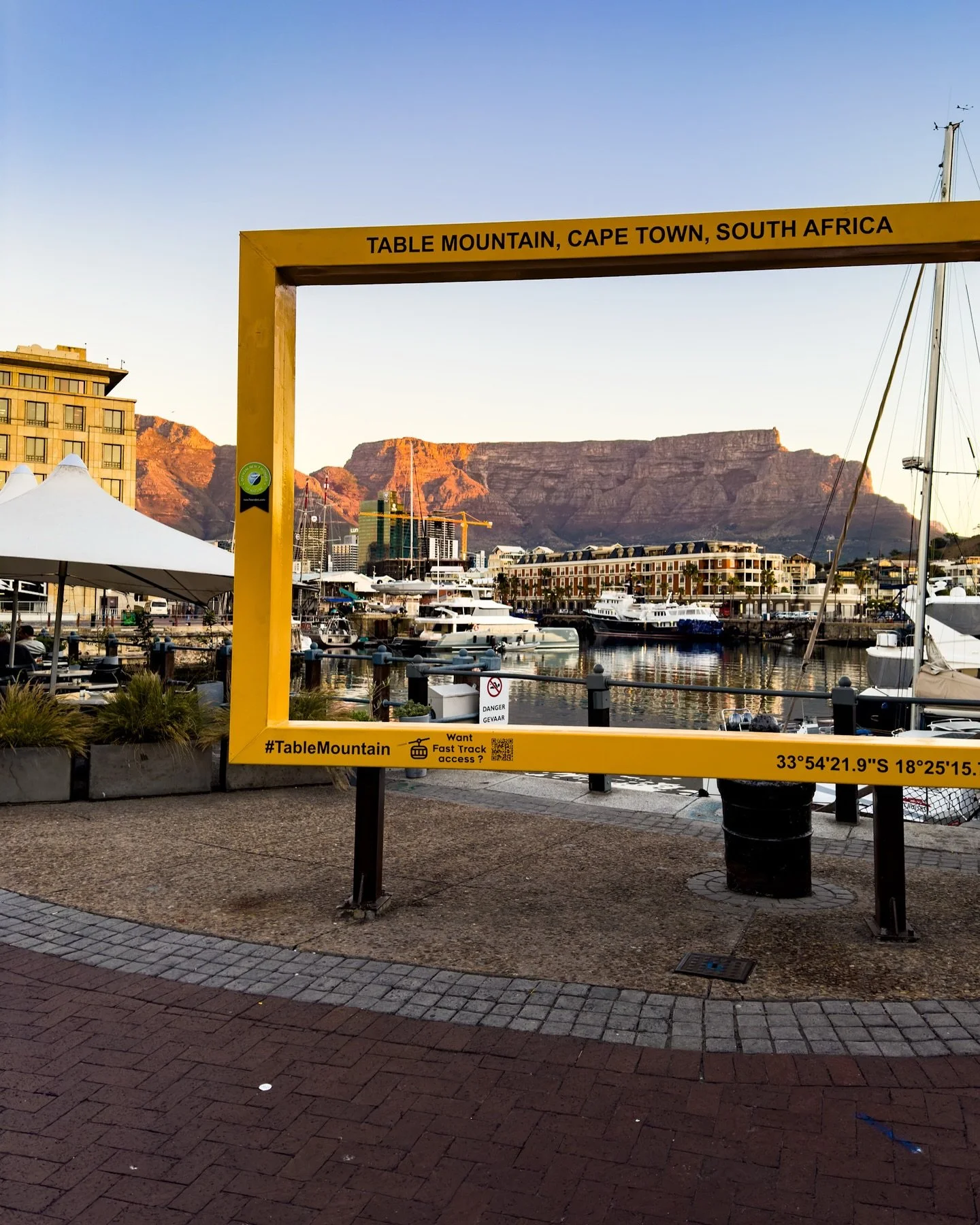 At the V&amp;A Waterfront, watching the sunset through the bright yellow Table Mountain frame &mdash; one of those perfect Cape Town views that never gets old.

The mountain in the distance, the sky turning gold, and the city winding down for the eve