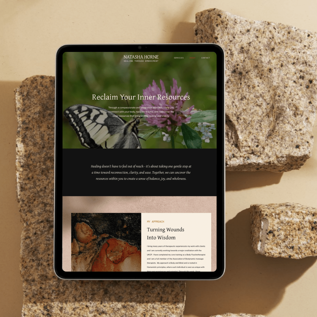 A tablet displaying a website with the title "Reclaim Your Inner Resources", on a surface surrounded by four large rocks.