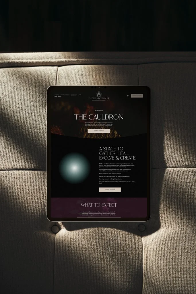 A tablet displaying a website about 'The Cauldron,' placed on a beige cushioned surface with shadows and a dark background.