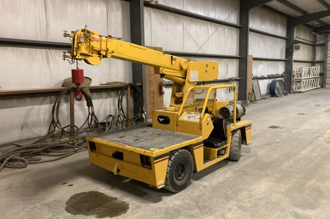Yellow industrial ladder lift inside a warehouse with concrete floors and metal walls