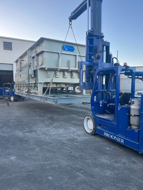 Blue forklift lifting a large industrial container outdoors