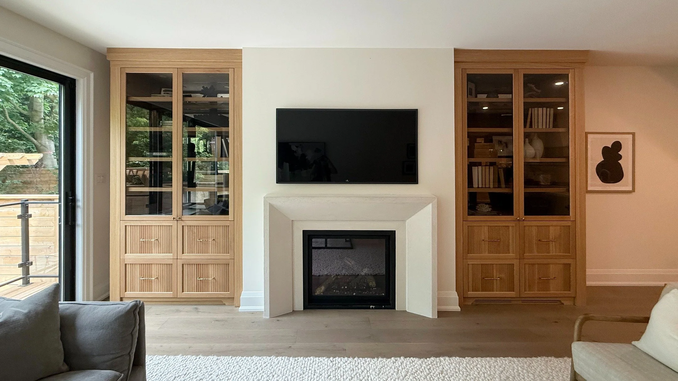 The living room features custom white oak built-ins, and a masterfully hand-plastered fireplace mantle. The fluted detailing, glass cabinet doors, and aged brass hardware give the piece both presence and softness.⁠

#CustomMillwork #InteriorDesignTor