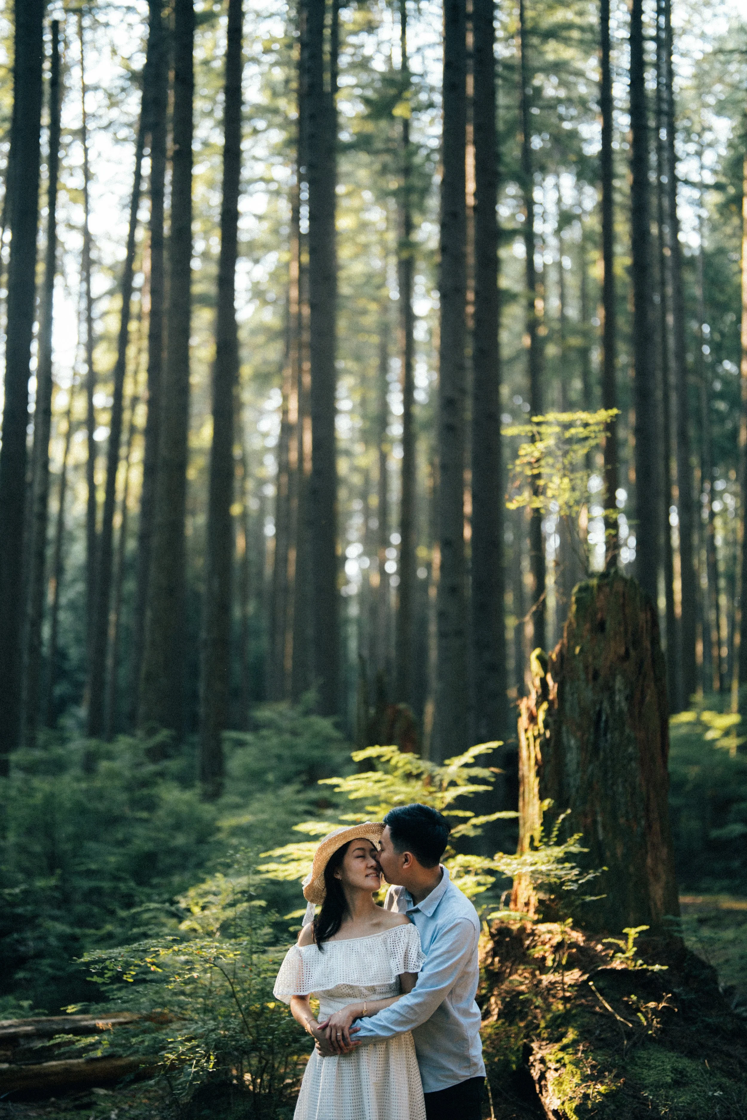  A tender kiss shared beneath the high forest canopy, emphasizing intimacy in the vast woods. 