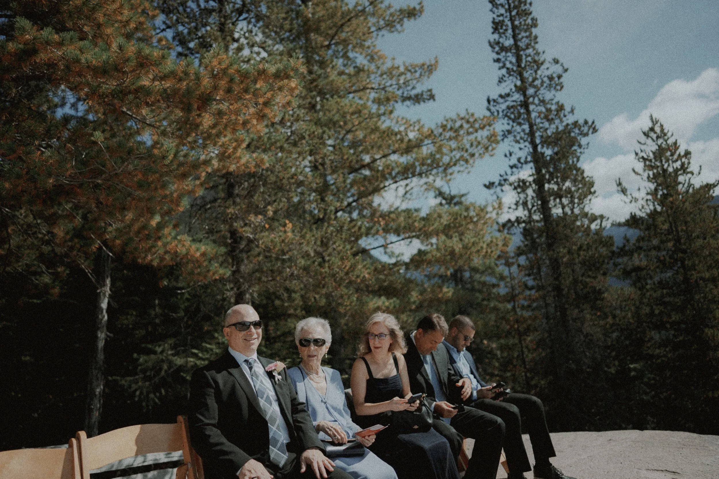 Wedding guests seated in sunshine among trees at Sea to Sky Gondola.