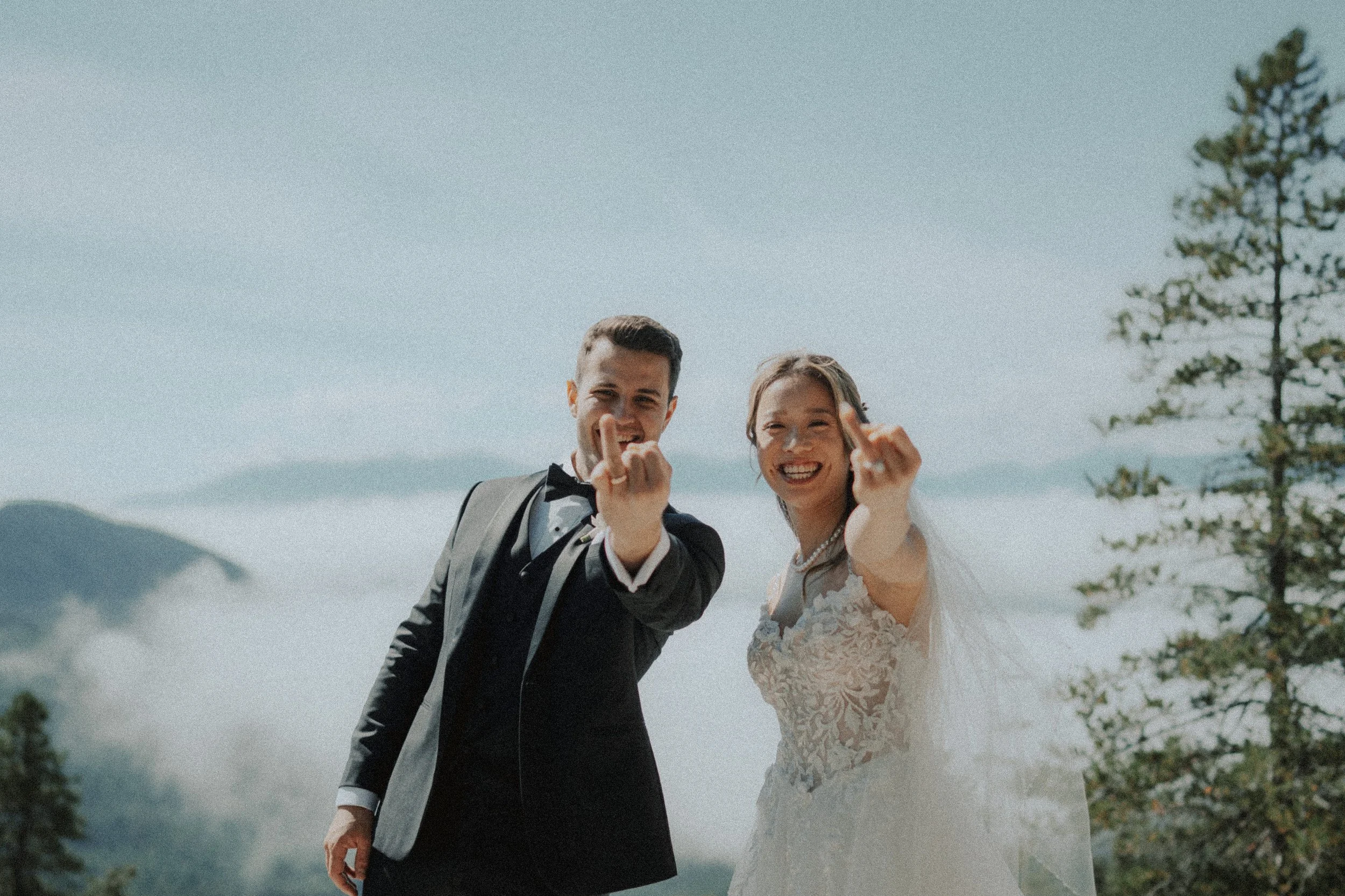 Bride and groom smiling as they hold up their wedding rings.